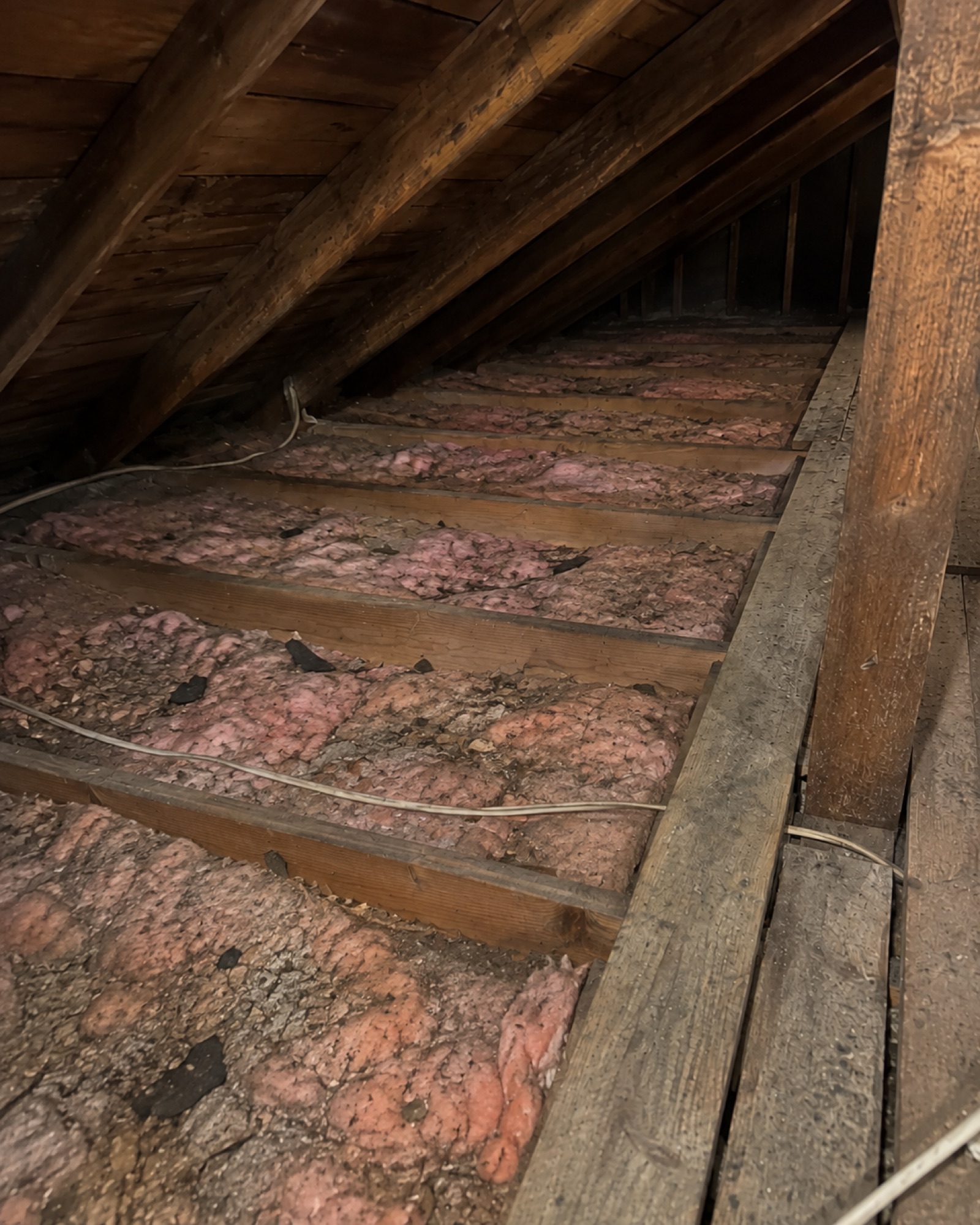 Old, thin attic insulation before an upgrade