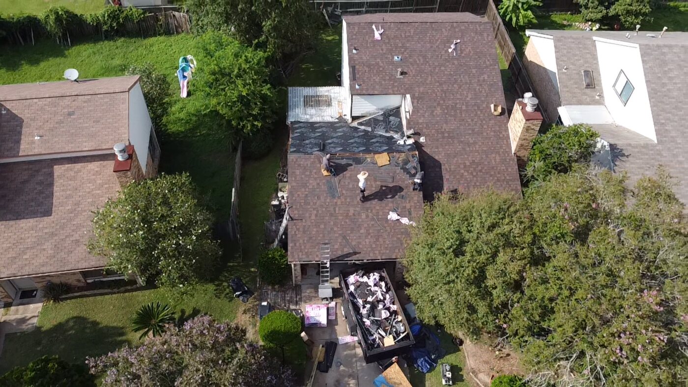 Aerial drone photo of a technician working on a roof during a tear-off