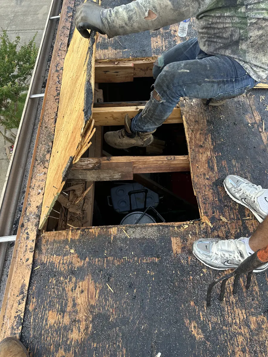 Damaged roof decking exposed and being repaired