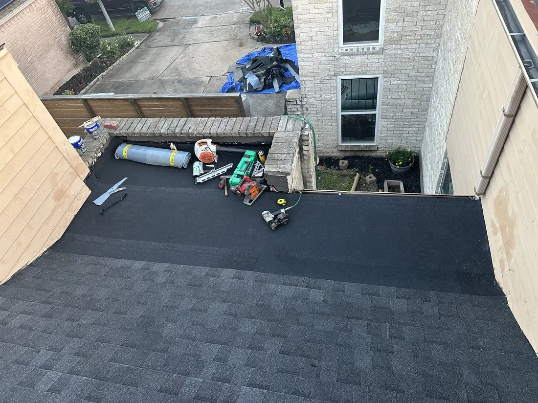 Roofer replacing flashing and underlayment along a roof-to-wall transition